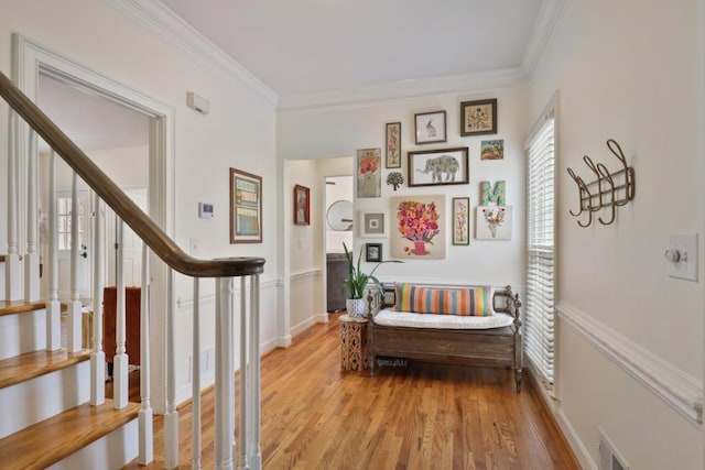 hall with visible vents, ornamental molding, light wood finished floors, baseboards, and stairs