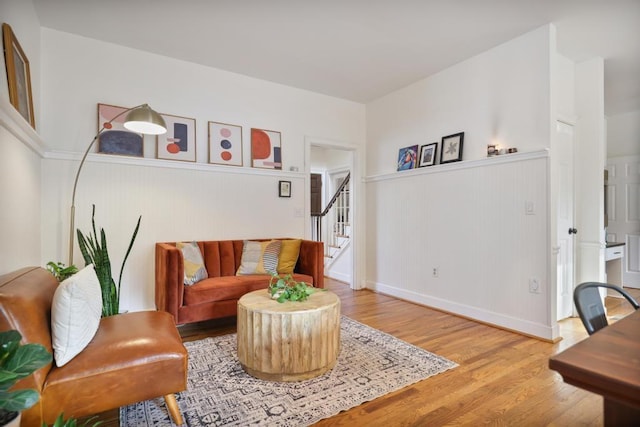 living room with stairway, a wainscoted wall, and wood finished floors