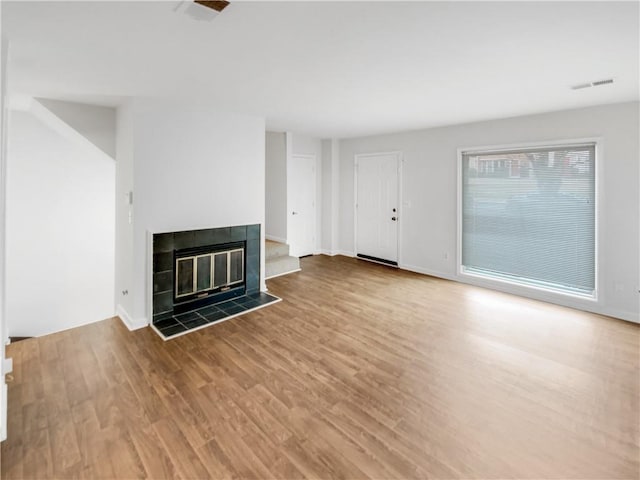 unfurnished living room featuring a tiled fireplace and wood-type flooring