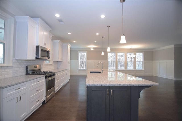 kitchen with a spacious island, white cabinets, stainless steel appliances, and decorative light fixtures