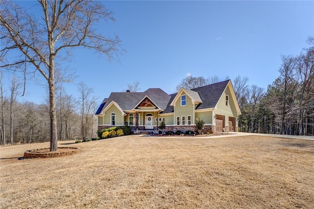 craftsman inspired home with a garage, driveway, and a front lawn