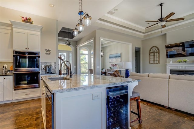 kitchen with double oven, wine cooler, open floor plan, and a sink