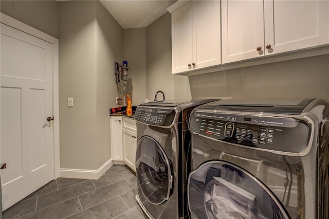 washroom featuring baseboards, cabinet space, and washer and clothes dryer