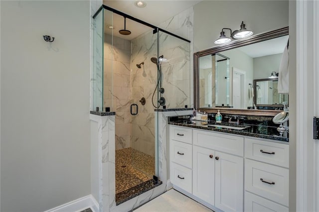 full bathroom featuring vanity, baseboards, and a marble finish shower