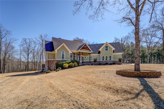 view of front facade featuring stone siding, a porch, and a front yard