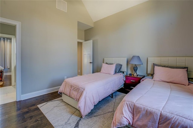 bedroom with visible vents, baseboards, high vaulted ceiling, and wood finished floors