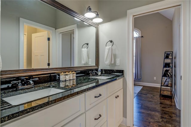 bathroom featuring a sink, baseboards, wood finished floors, and double vanity