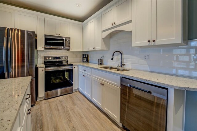 kitchen featuring tasteful backsplash, appliances with stainless steel finishes, light wood-style floors, and a sink