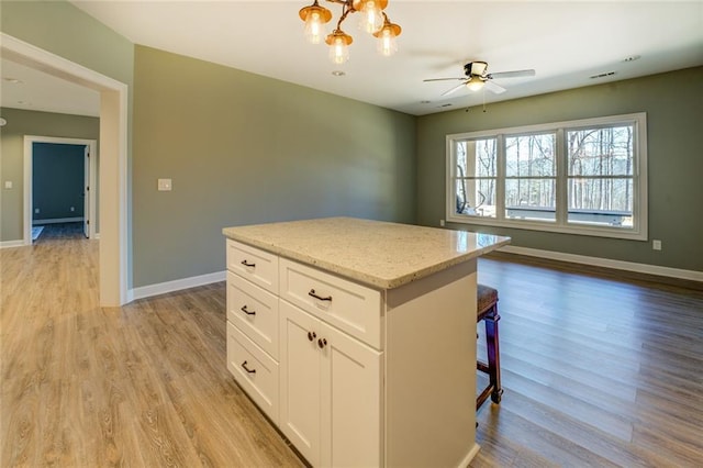 kitchen featuring light wood-type flooring, baseboards, and white cabinetry