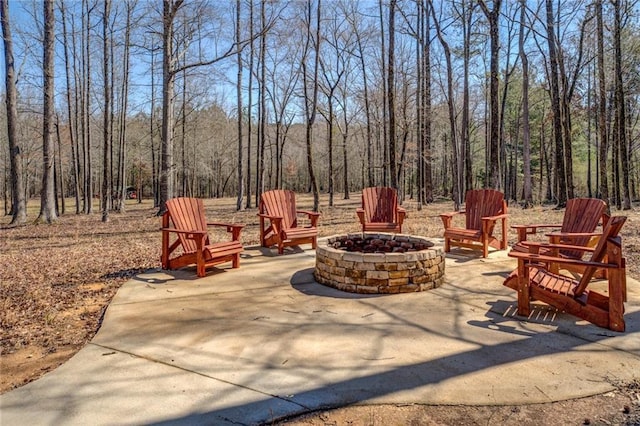 view of patio with a fire pit and a view of trees