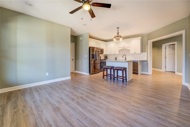 living area featuring light wood-style flooring, a ceiling fan, and baseboards