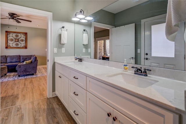 full bathroom with a ceiling fan, double vanity, wood finished floors, and a sink