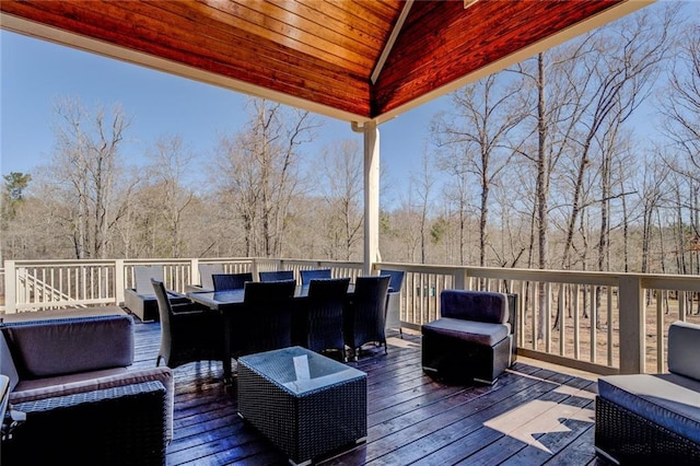 wooden deck featuring outdoor dining space and a forest view