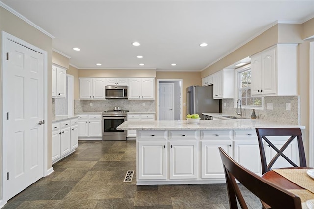 kitchen featuring a sink, stainless steel appliances, a peninsula, and white cabinetry