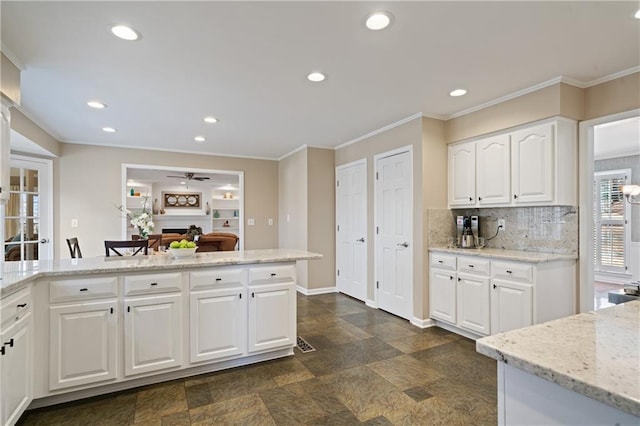 kitchen with a fireplace, crown molding, and light stone countertops