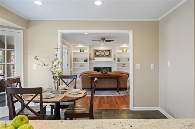 dining space with built in shelves, baseboards, recessed lighting, a fireplace, and crown molding