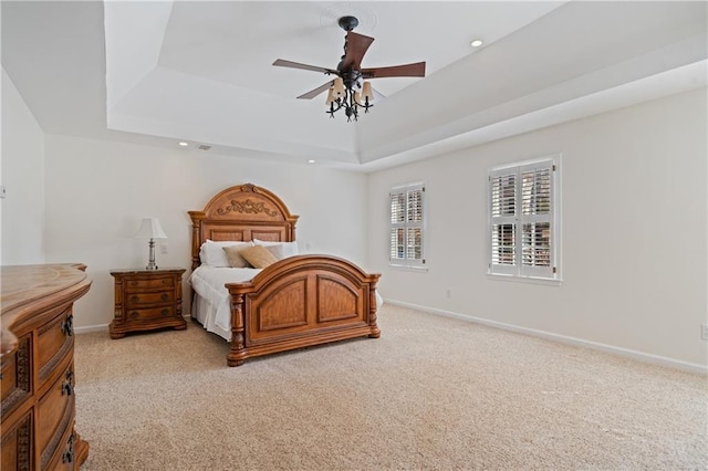 bedroom with a tray ceiling, recessed lighting, baseboards, and light carpet