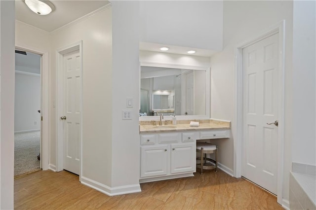 bathroom with vanity, crown molding, and baseboards