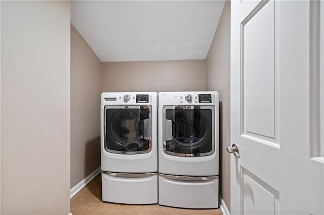 clothes washing area with laundry area, washing machine and dryer, and baseboards