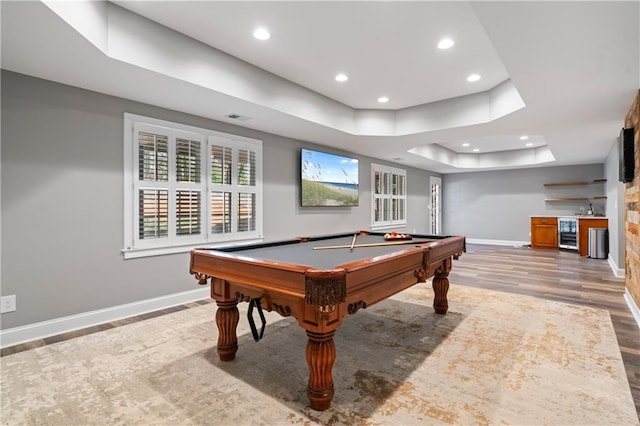 rec room with wine cooler, a tray ceiling, baseboards, and wood finished floors