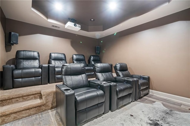 cinema featuring baseboards, a raised ceiling, visible vents, and wood finished floors