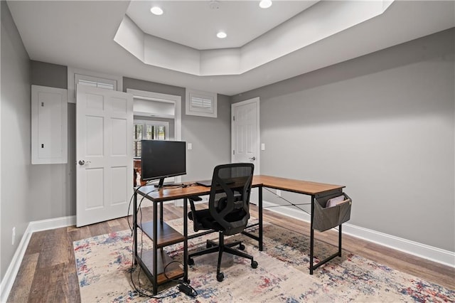 office area featuring recessed lighting, a raised ceiling, baseboards, and wood finished floors