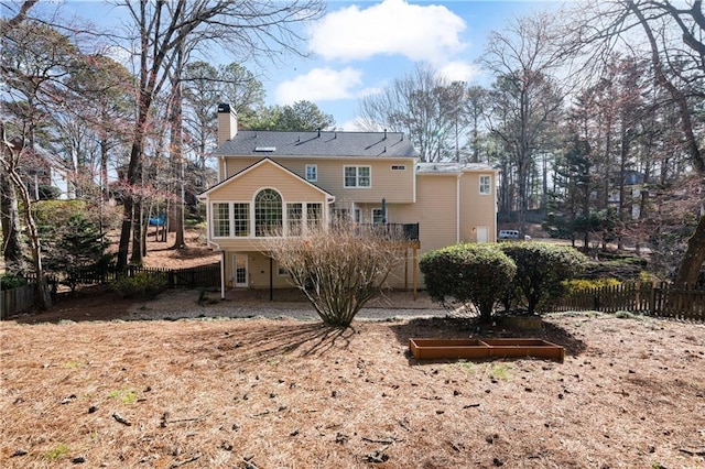 rear view of property with a chimney, a deck, and fence