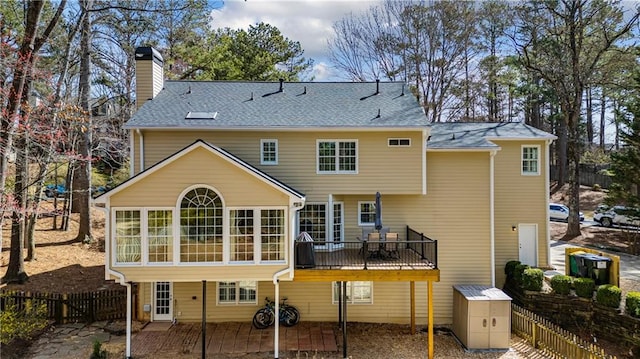 rear view of property with fence, a sunroom, a wooden deck, a chimney, and a patio area