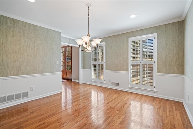 unfurnished dining area featuring a wainscoted wall, visible vents, and hardwood / wood-style floors