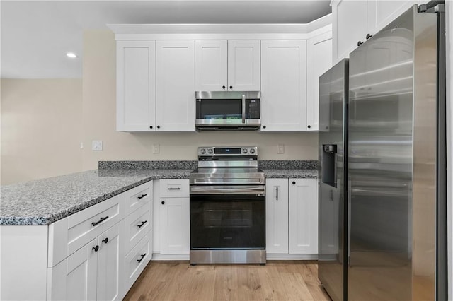 5232 W Mountain St, Stone Mountain, GA 30083 - kitchen featuring appliances with stainless steel finishes, a peninsula, white cabinetry, light wood-type flooring, and recessed lighting