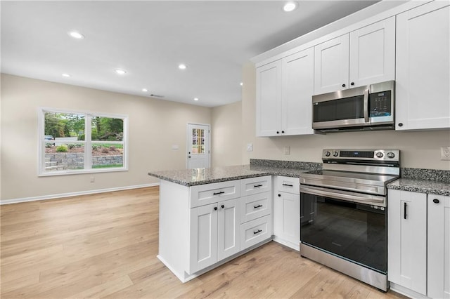 5232 W Mountain St, Stone Mountain, GA 30083 - kitchen with appliances with stainless steel finishes, a peninsula, white cabinets, recessed lighting, and light wood-type flooring