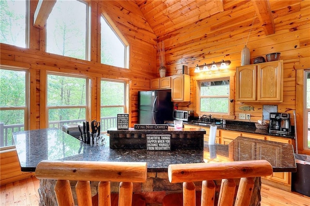 kitchen with light brown cabinetry, stainless steel microwave, light wood finished floors, and freestanding refrigerator