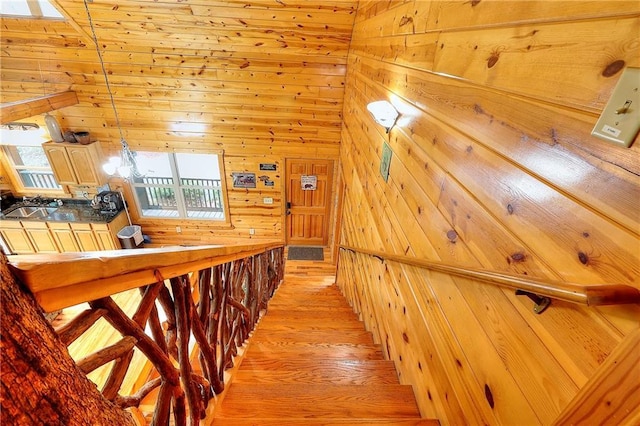 stairway with wooden walls and wood finished floors