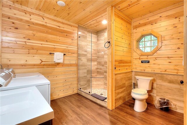 bathroom featuring wooden ceiling, independent washer and dryer, toilet, a stall shower, and wood finished floors