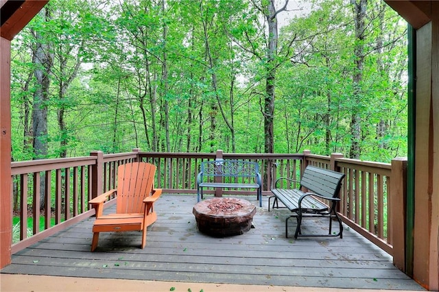wooden terrace featuring a fire pit and a view of trees