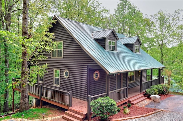 view of front of home featuring covered porch, metal roof, and log veneer siding