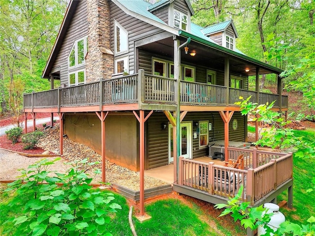 back of property with metal roof, a wooden deck, and log veneer siding