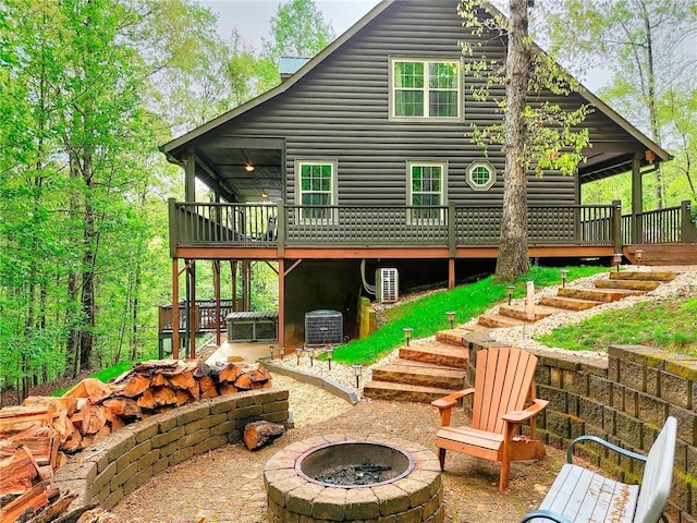 back of property with an outdoor fire pit, a wooden deck, a patio area, central AC, and stairs