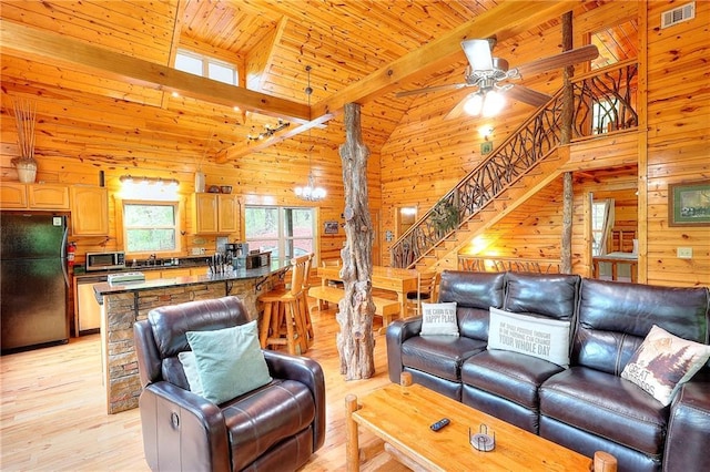 living room with light wood finished floors, visible vents, stairway, and wood walls