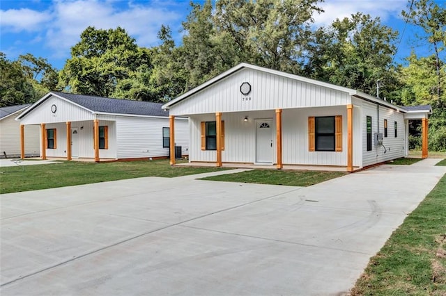 modern inspired farmhouse featuring a porch, a front yard, concrete driveway, and roof with shingles