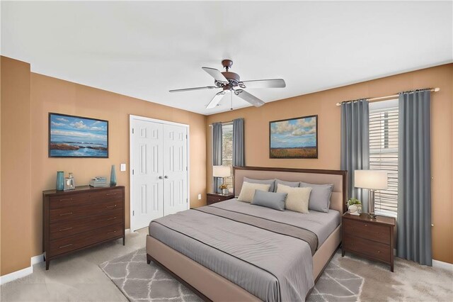 bedroom with ceiling fan, a closet, light colored carpet, and multiple windows