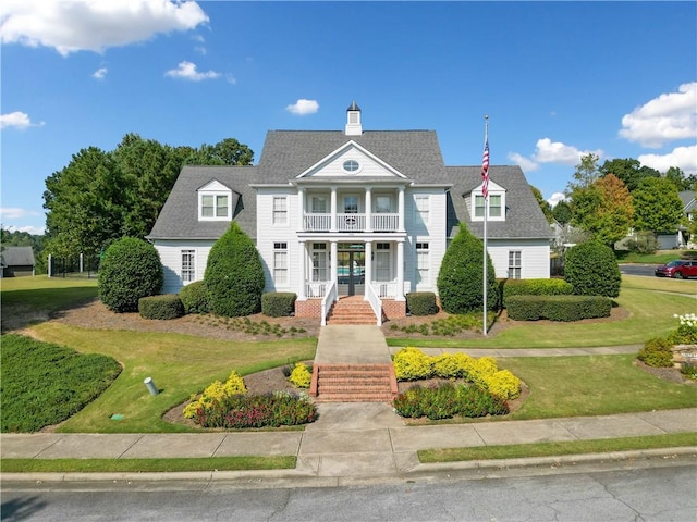 view of front facade with covered porch, a balcony, and a front yard