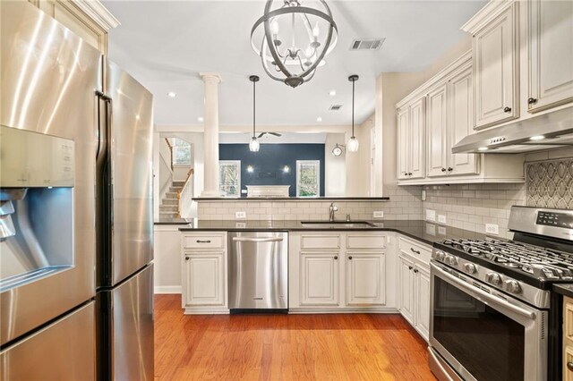 kitchen with backsplash, sink, hanging light fixtures, light hardwood / wood-style flooring, and stainless steel appliances