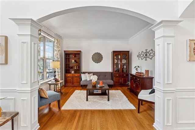 living room with ornamental molding, wood-type flooring, and ornate columns