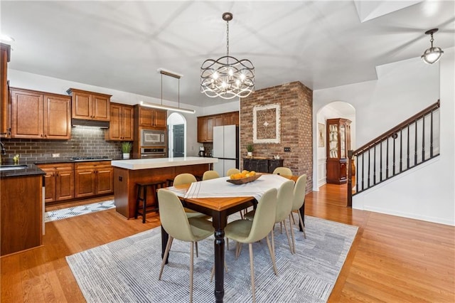 dining area featuring sink, a chandelier, and light wood-type flooring