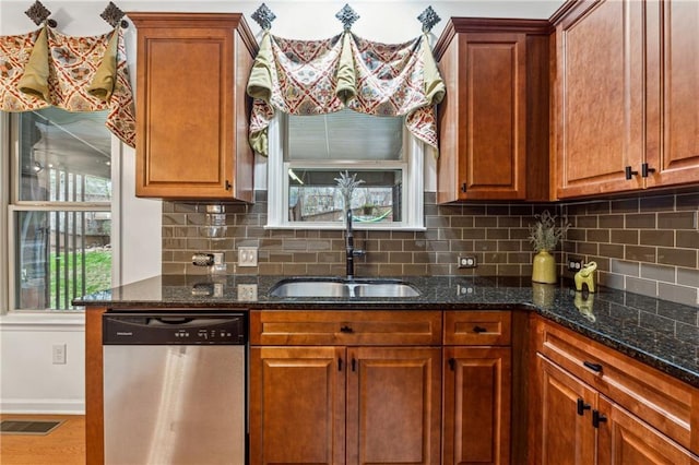 kitchen with sink, hardwood / wood-style flooring, dishwasher, dark stone countertops, and decorative light fixtures