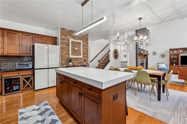 kitchen with tasteful backsplash, a center island, hanging light fixtures, white refrigerator, and a fireplace