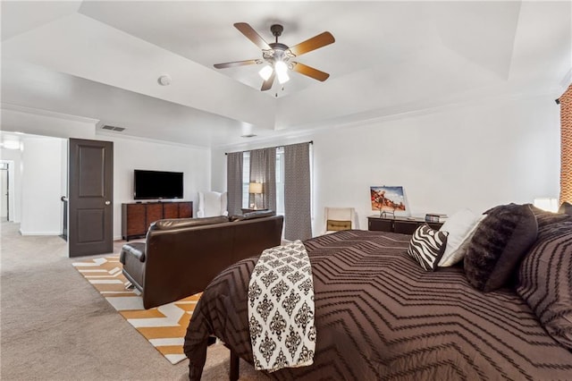 carpeted bedroom with crown molding, ceiling fan, and a tray ceiling