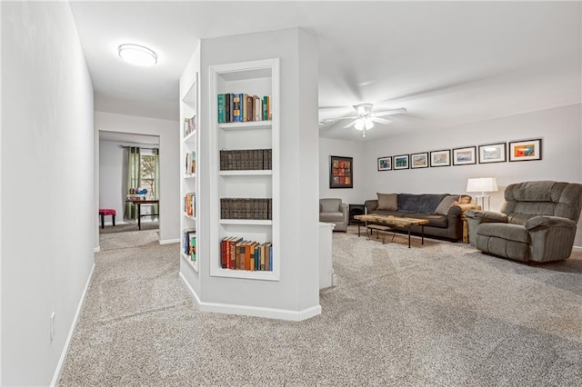 carpeted living room featuring built in shelves and ceiling fan