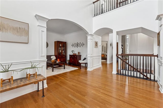 foyer with a towering ceiling, light hardwood / wood-style floors, and ornate columns